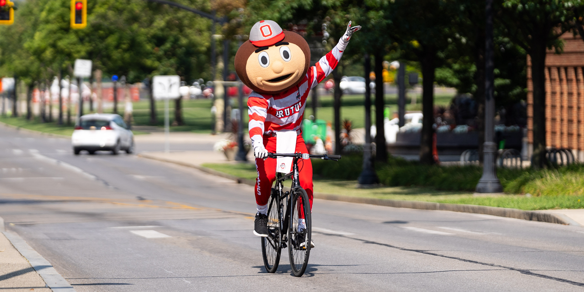 Brutus Buckeye riding a bike